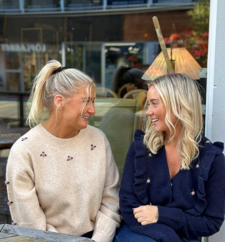 Bilde av to ansatte fra Klara Tønsberg som sitter og smiler til hverandre