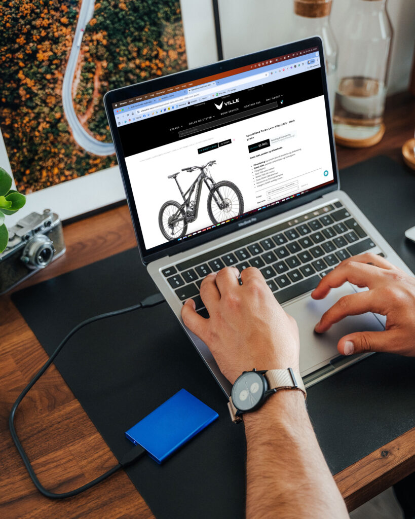 Close up fra en kontorpult hvor det står en laptop som viser hjemmesiden til villesykler.no
