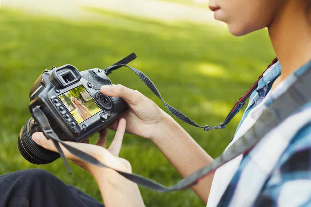 Bilde av en kvinne som tar bilder med speilreflekskamera. Bildene blir brukt til hvorfor markedsføre i sosiale medier